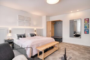 A modern bedroom with a bed, bedside table, bench, wardrobe, and a mirror. - Hotel Bad Minden (Minden)