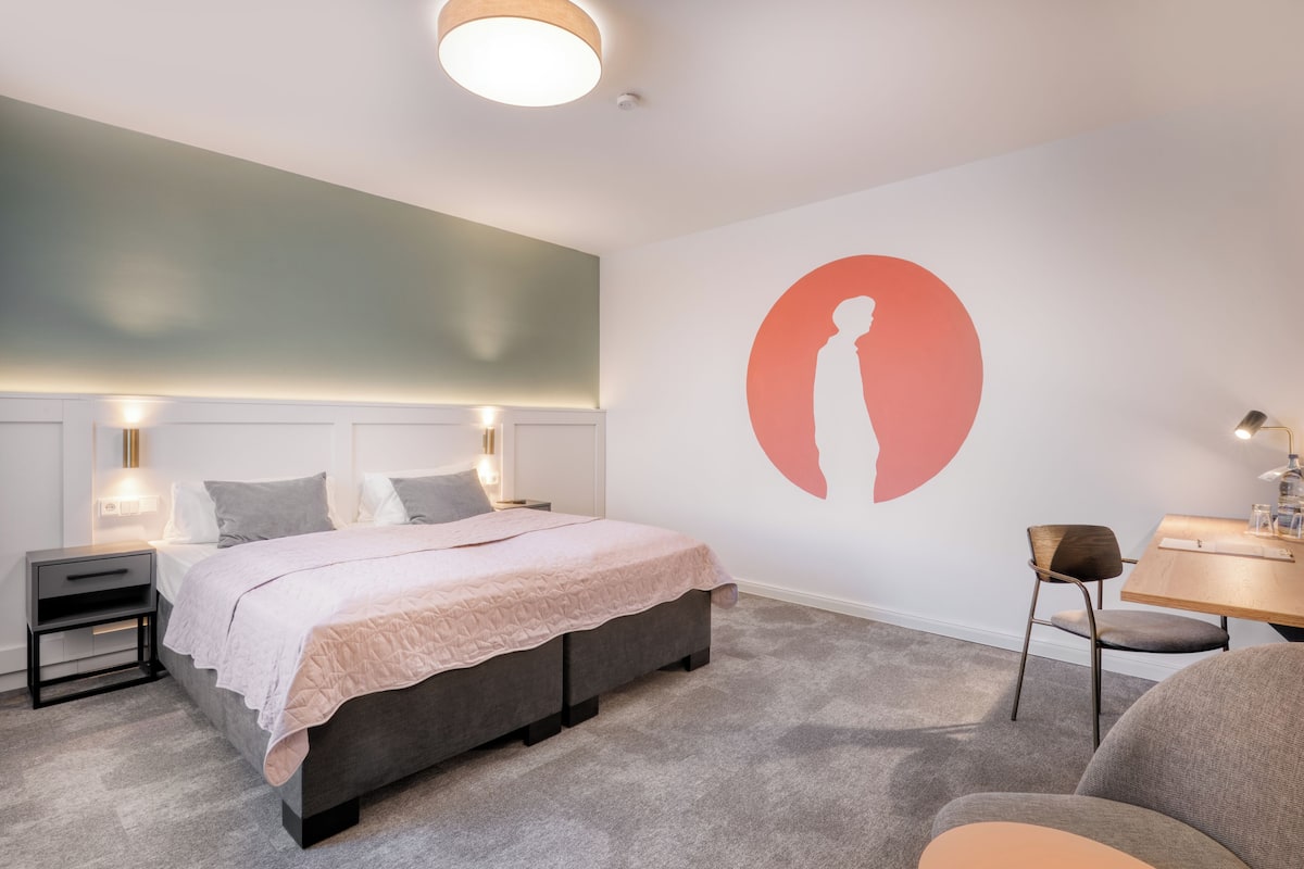 A modern bedroom with a bed, bedside tables, a desk, and a chair.