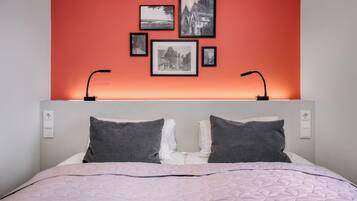 Un dormitorio con cama, almohadas, cabecera y cuadros en la pared.