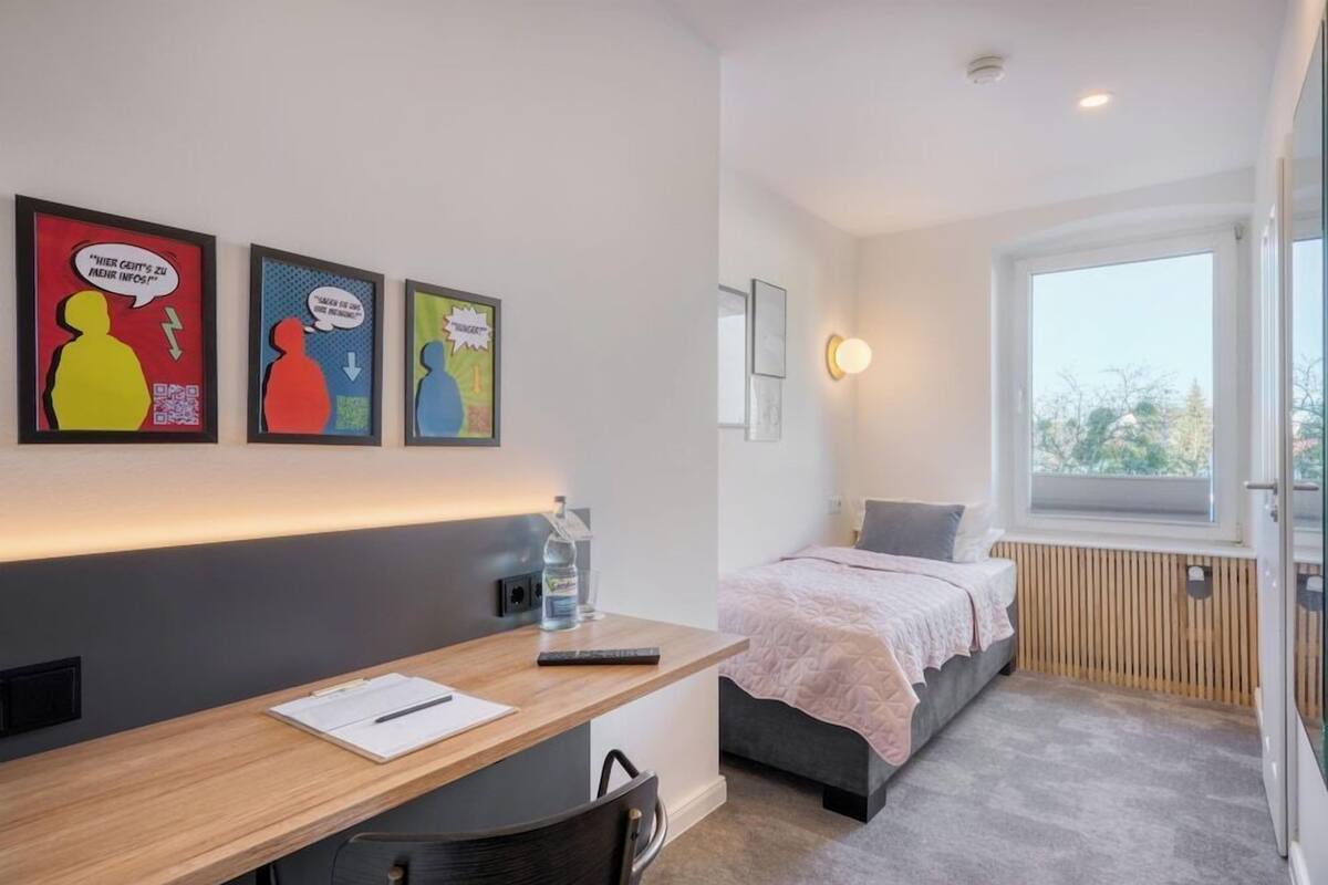 A modern room with a desk, bed, and artwork on the wall.