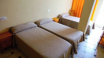 A room with two single beds, a wooden nightstand, a chair, and a small table.