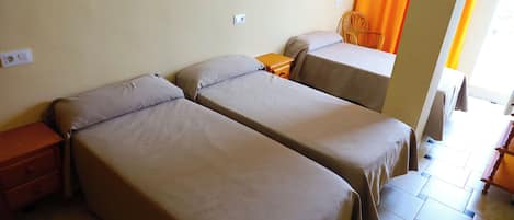 A room with two single beds, a wooden nightstand, a chair, and a small table.