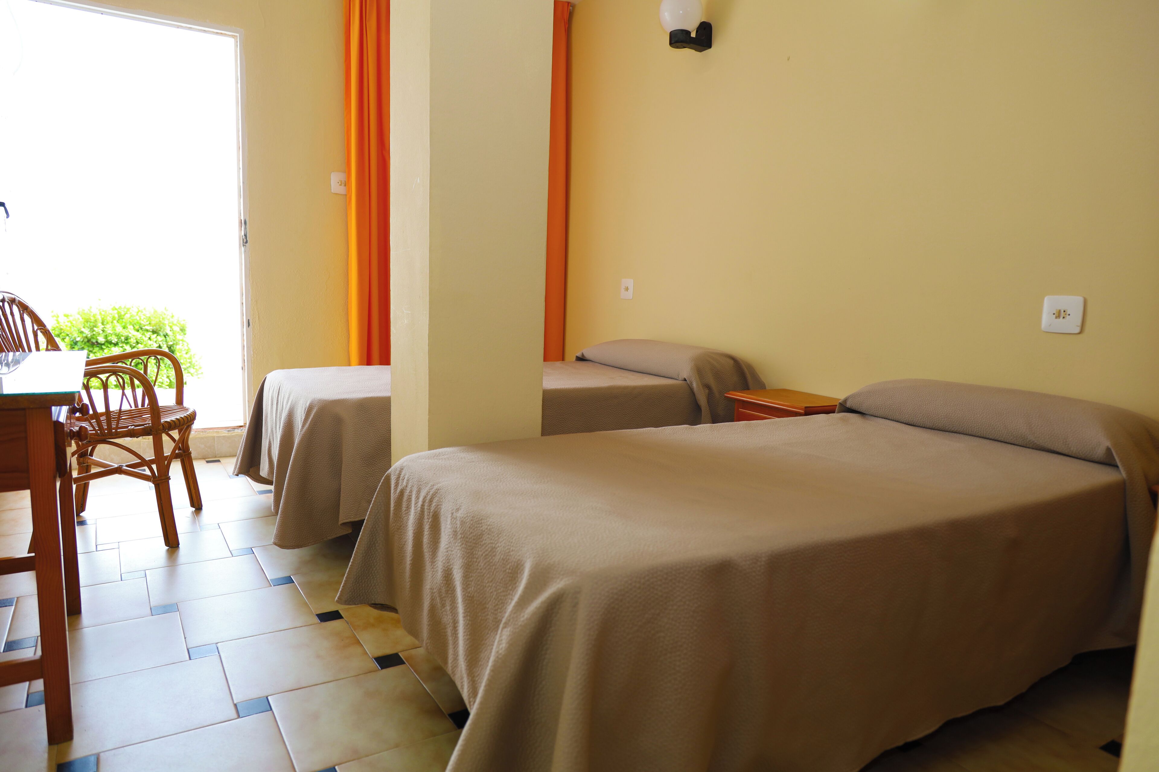 Una habitación con dos camas, una mesa y sillas.
