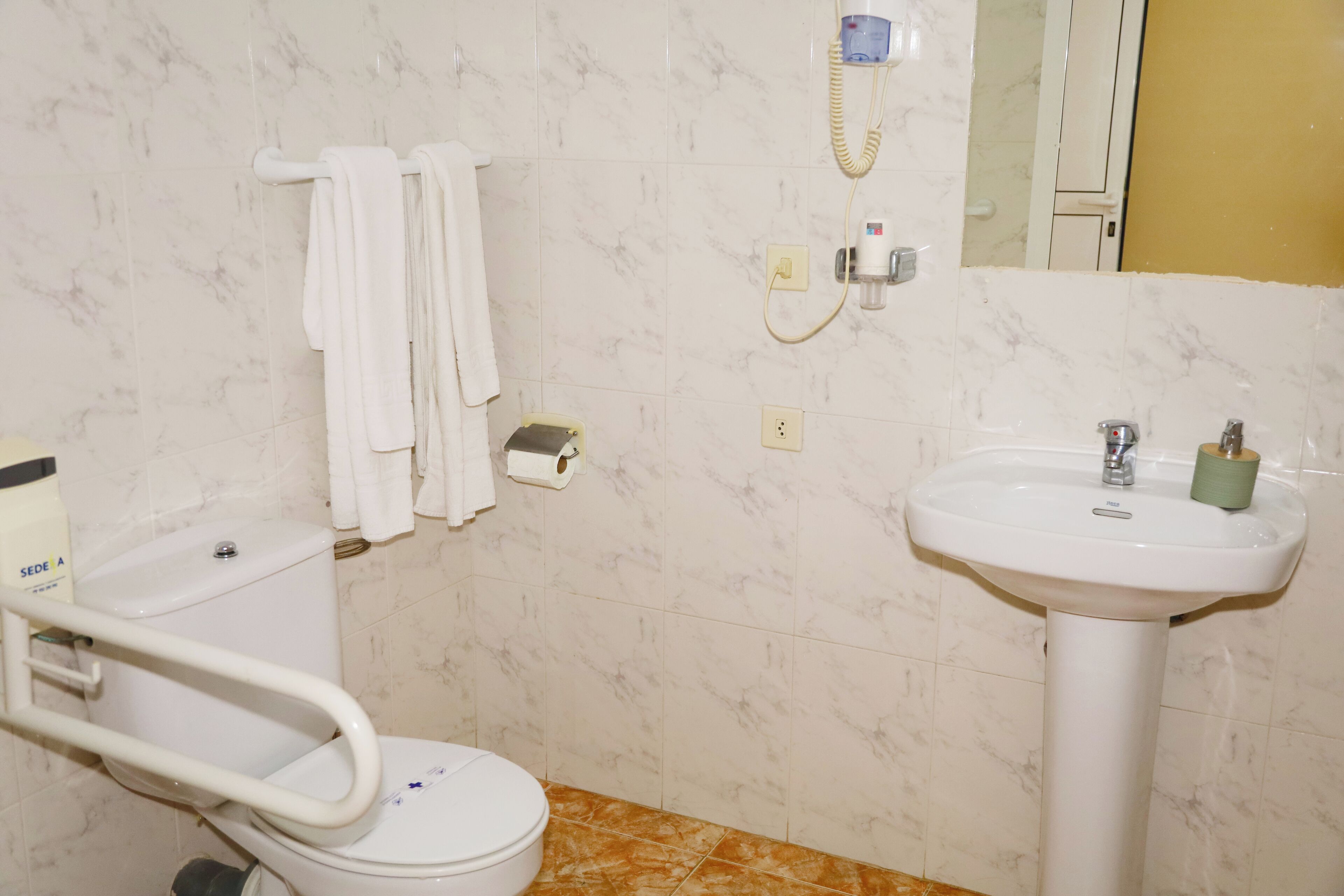 Un bany amb vàter, un lavabo, un assecagats mans i un mirall.