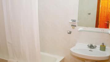 Un baño con bañera, lavamanos y espejo.