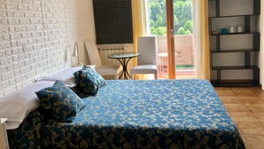 A bedroom with a bed, a chair, a small table, and a balcony with a view of greenery. - Affittacamere Alle 5 Terre (Monterosso al Mare)
