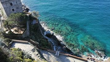 A coastal view with a stone building and a clear blue sea.