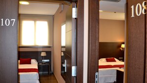 A hotel room with a bed, a desk, and a window. The room number is 107. - Hotel Vilassar (Vilassar de Mar)