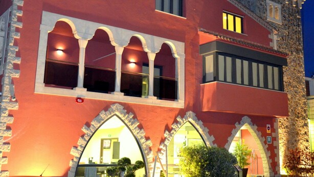 A building with a red facade, arched windows, and a stone tower. - Hotel Vilassar (Vilassar de Mar)