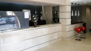 A reception area with a counter, a vase with flowers, and a parking view. - Hotel Vilassar (Vilassar de Mar)
