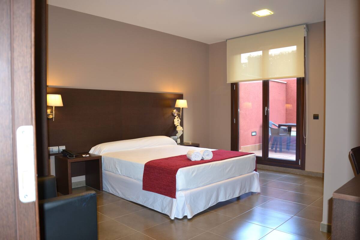 A hotel room with a large bed, two bedside tables with lamps, a small desk, and a chair.