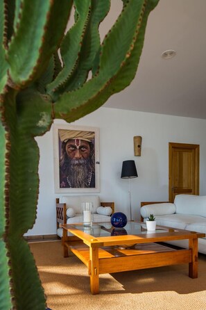 A living room with a wooden coffee table, white sofa, and a painting on the wall.