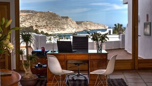 A modern office with a desk, two chairs, a laptop, and a view of a coastal landscape. - Boutique Hotel El Tio Kiko (Nijar)