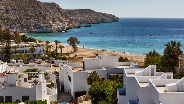 A coastal residential area with white buildings, a beach, and a rocky cliff. - Boutique Hotel El Tio Kiko (Nijar)
