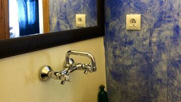 Ein Badezimmer mit einem weißen Waschbecken, einem Spiegel und einer blauen Wand mit Struktur.