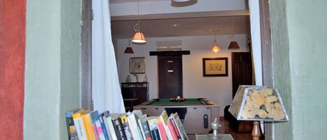 A room with a pool table, books, and a lamp.