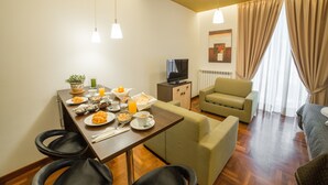 Una sala de estar moderna con comedor, sofá, televisor y ventana con cortinas.