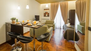 Una habitación de hotel con comedor, sofá, televisión y espejo.