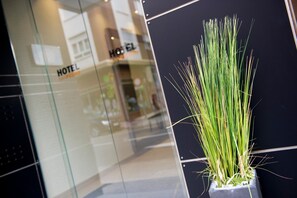 A hotel interior with a modern design, featuring a glass facade and a potted plant in the foreground. - San Pedro (Langreo)