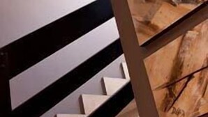 A staircase with a black railing and a painting on the wall. - San Pedro (Langreo)