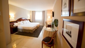 A hotel room with a double bed, bedside tables, a desk with a chair, a small table with a vase, and framed pictures on the wall. - San Pedro (Langreo)