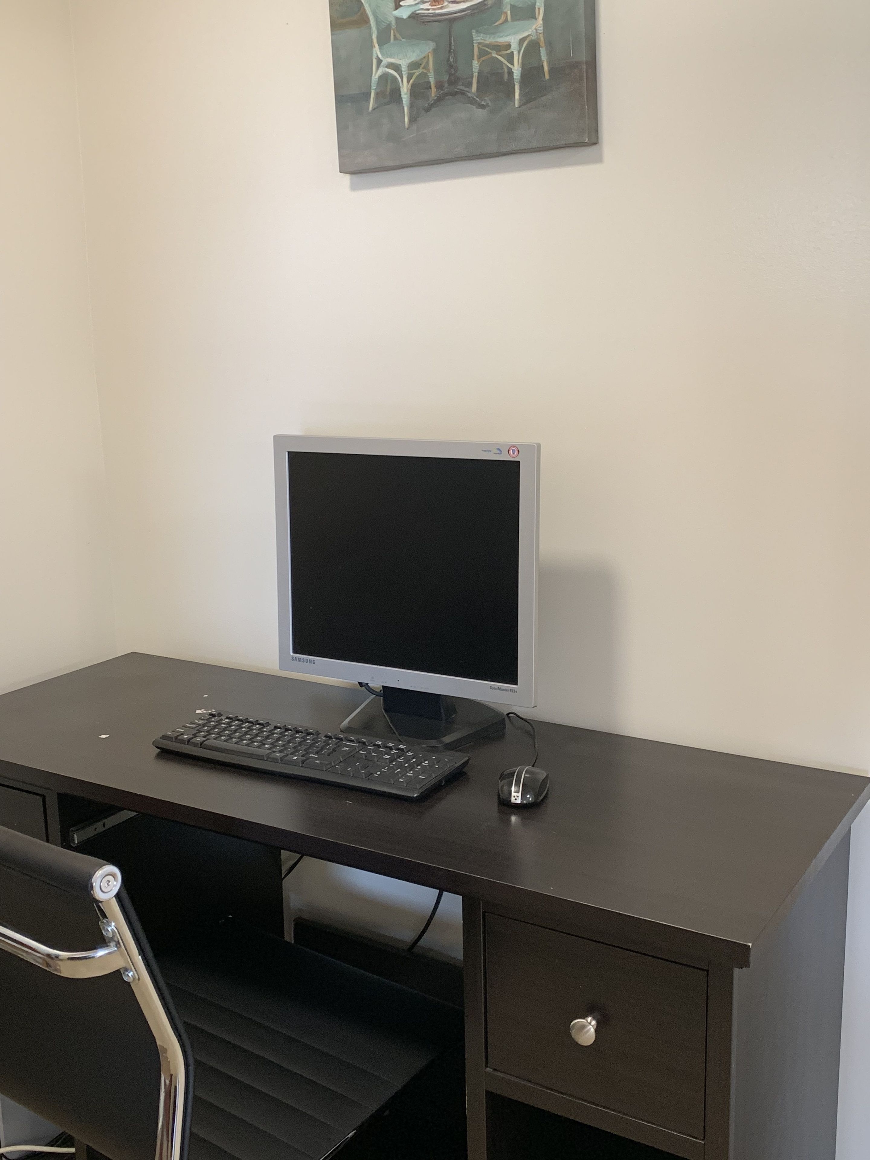 Un escritorio de madera oscura con un monitor Samsung, teclado y ratón.
