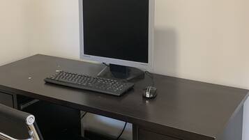 Un escritorio de madera oscura con un monitor Samsung, teclado y ratón.