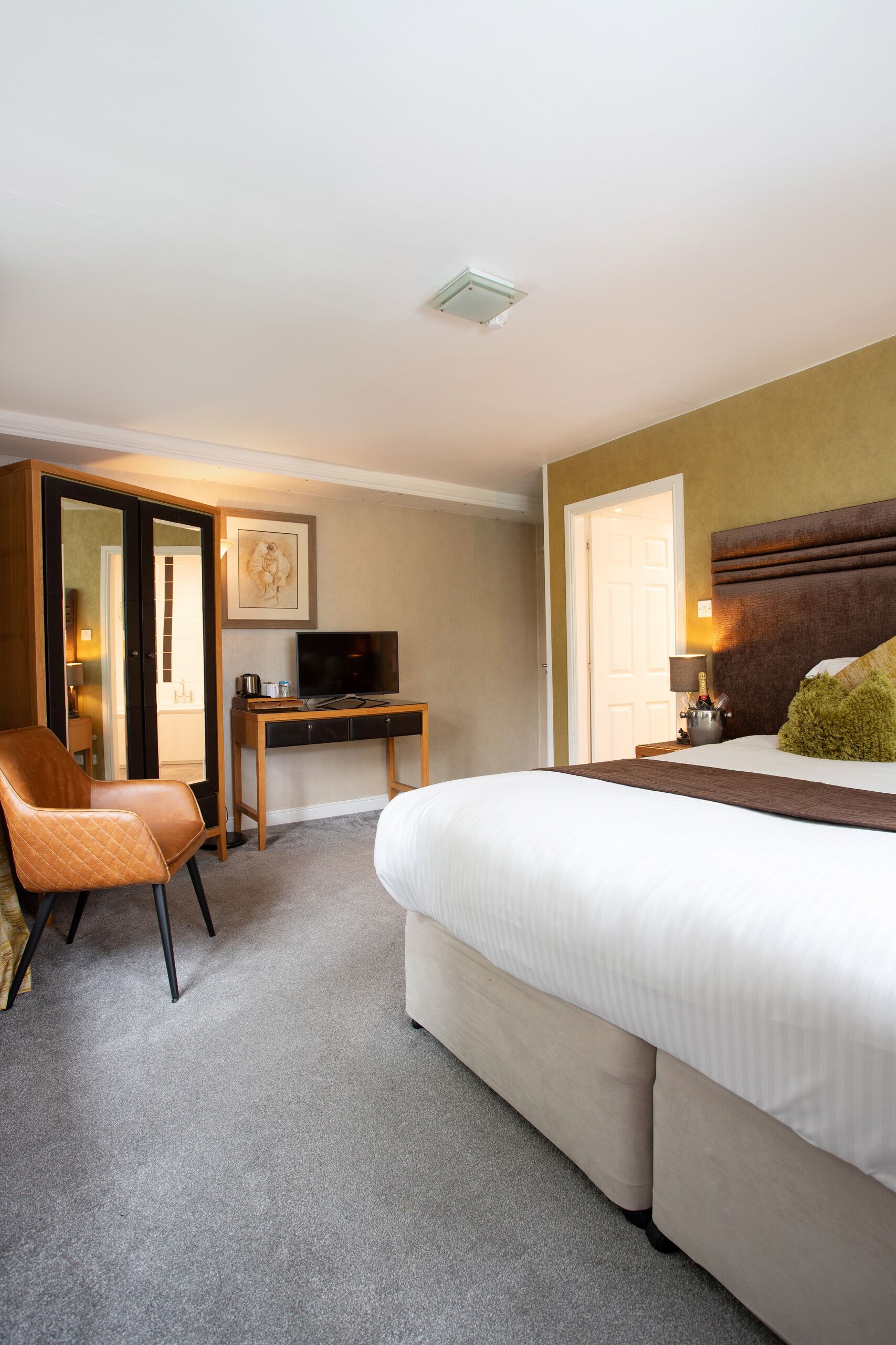 Ein Hotelzimmer mit Bett, Schreibtisch, Stuhl, Fernseher und Tür.