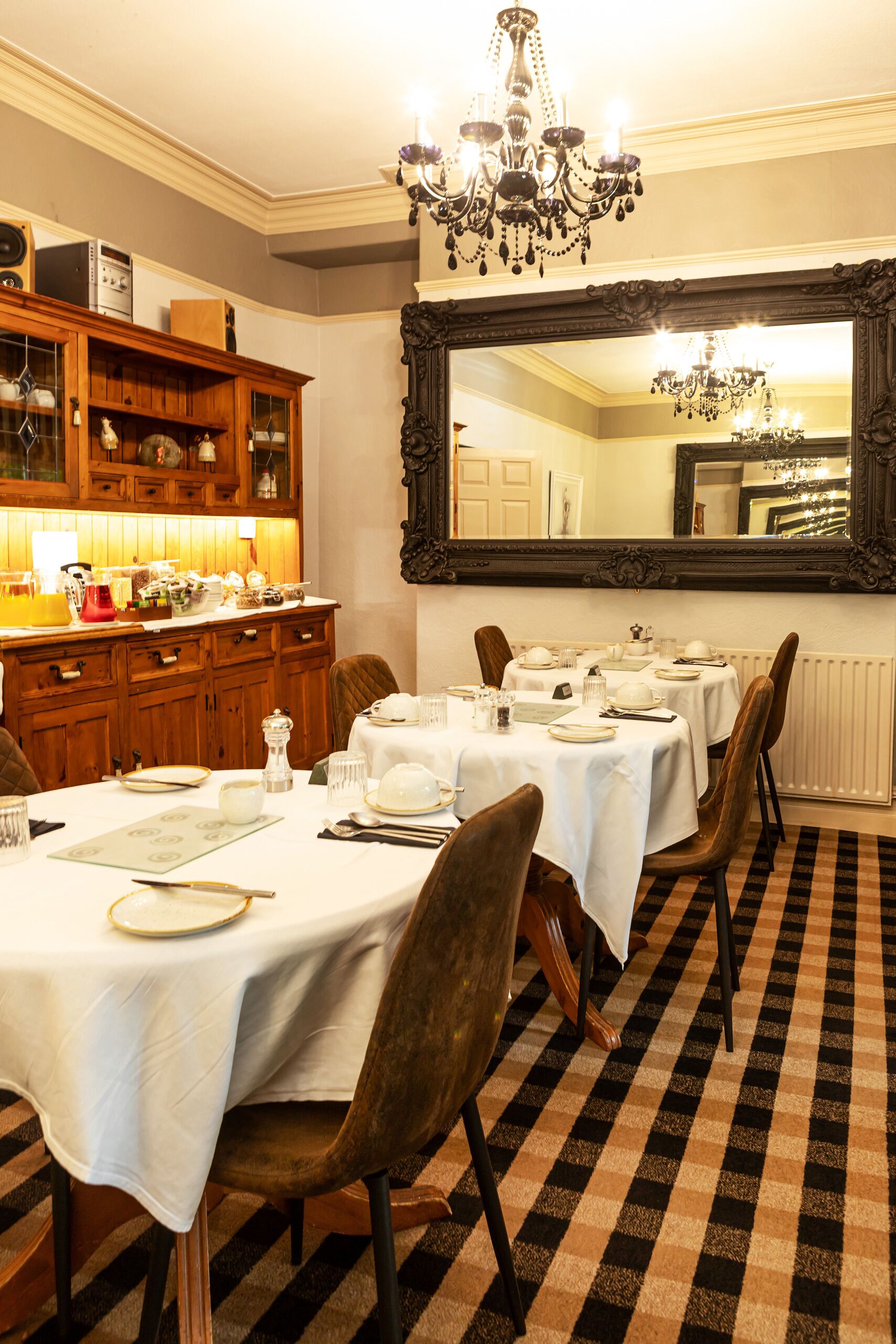 A dining area with a large mirror, wooden cabinets, and a checkered floor.