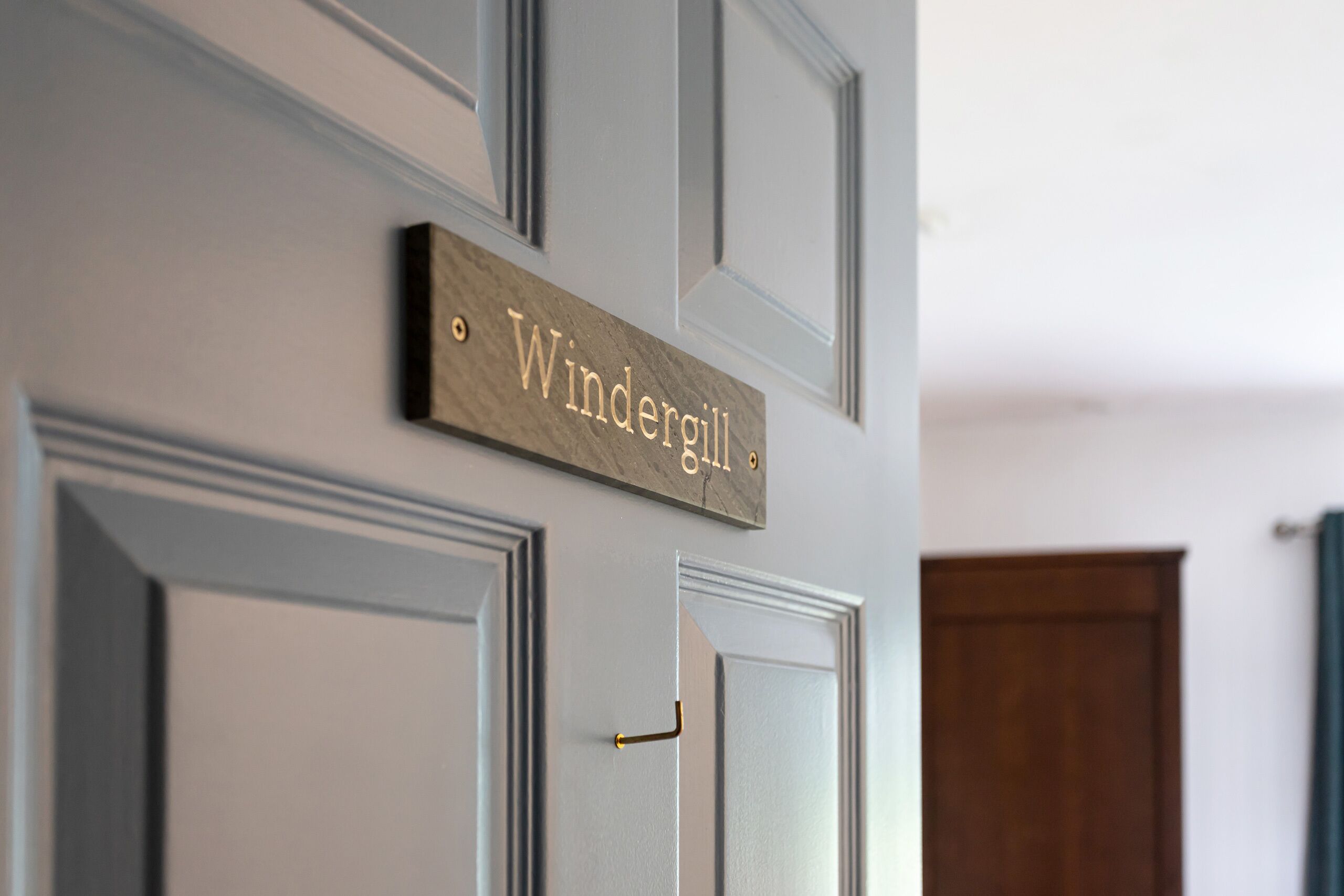 A door with a nameplate reading 'Windergill' and a brass handle.