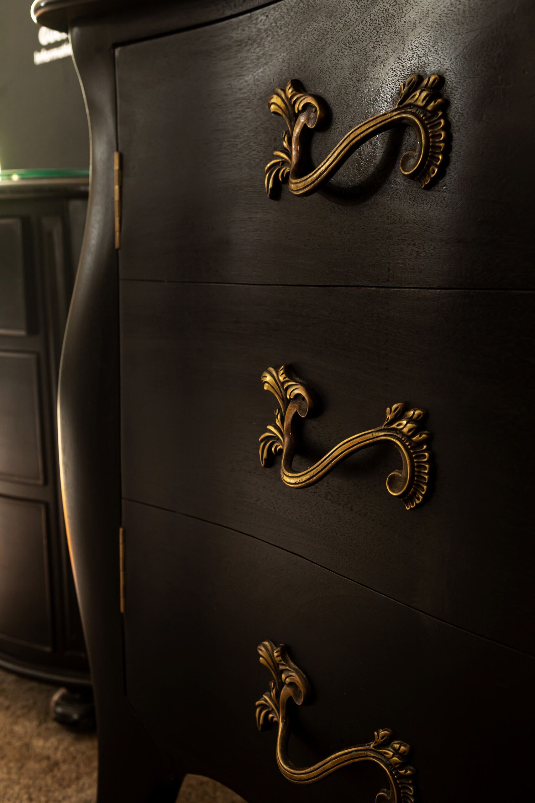 Primer plano de un aparador negro con tiradores dorados decorativos.