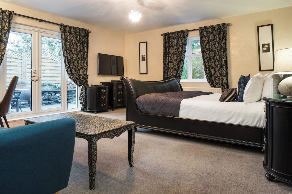 A bedroom with a bed, a desk, a chair, a dresser, and a TV.