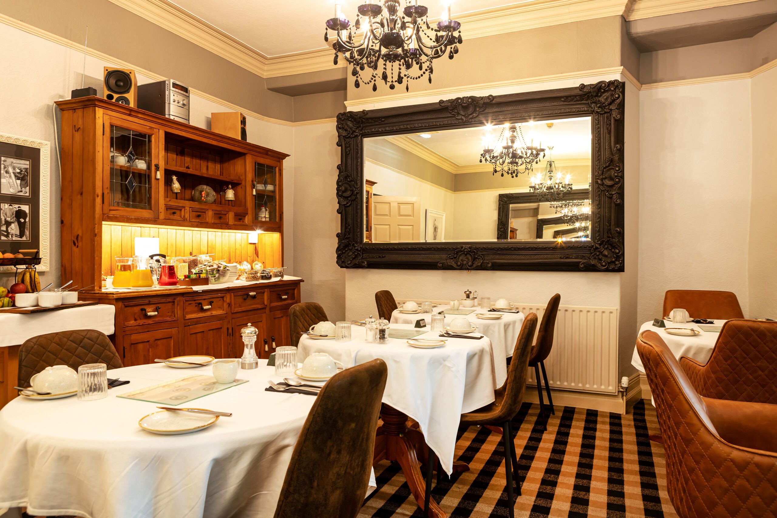 A dining room with a large mirror, wooden cabinets, and a chandelier.