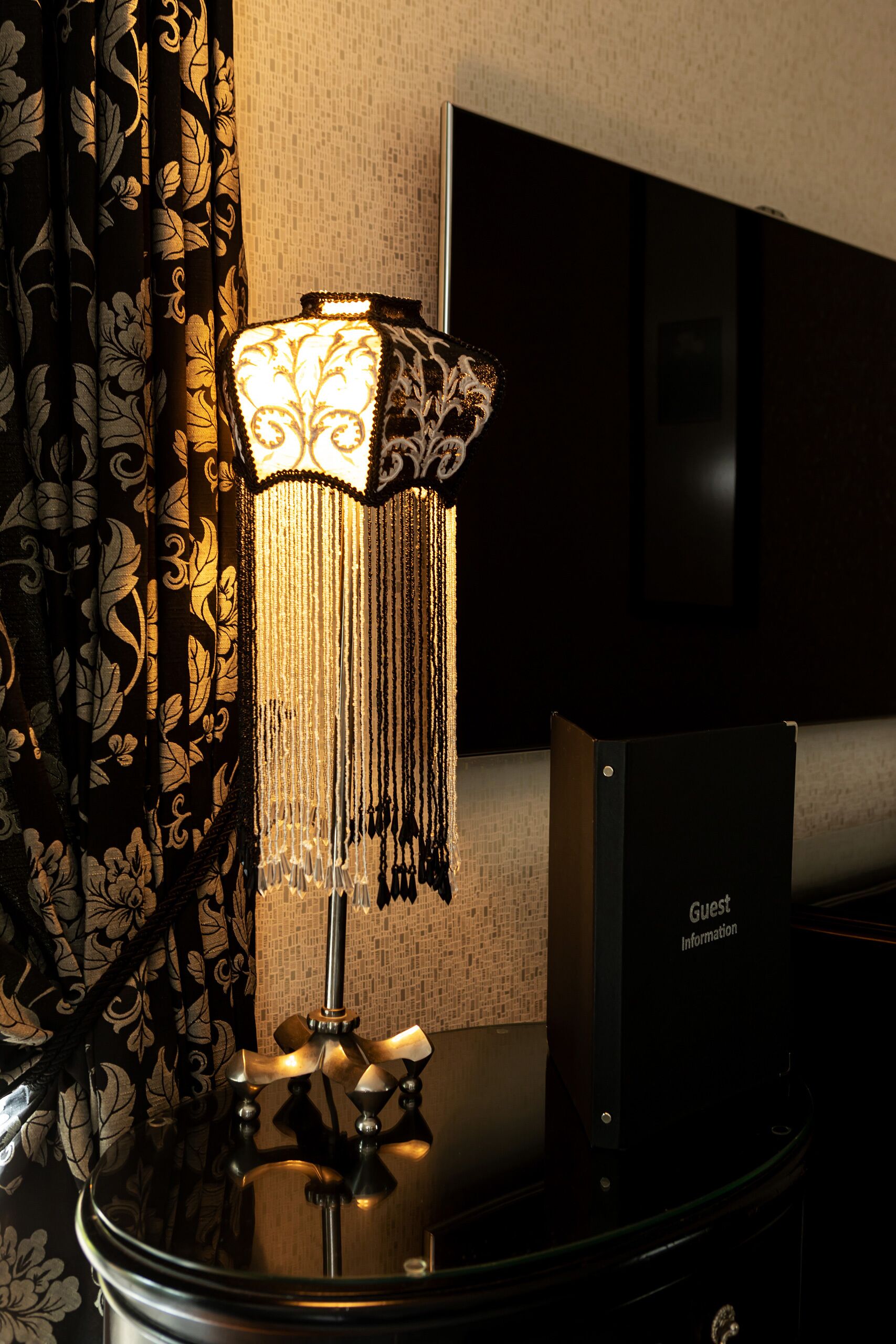 A room with a table lamp, a flat-screen TV, and a 'Guest Information' box.