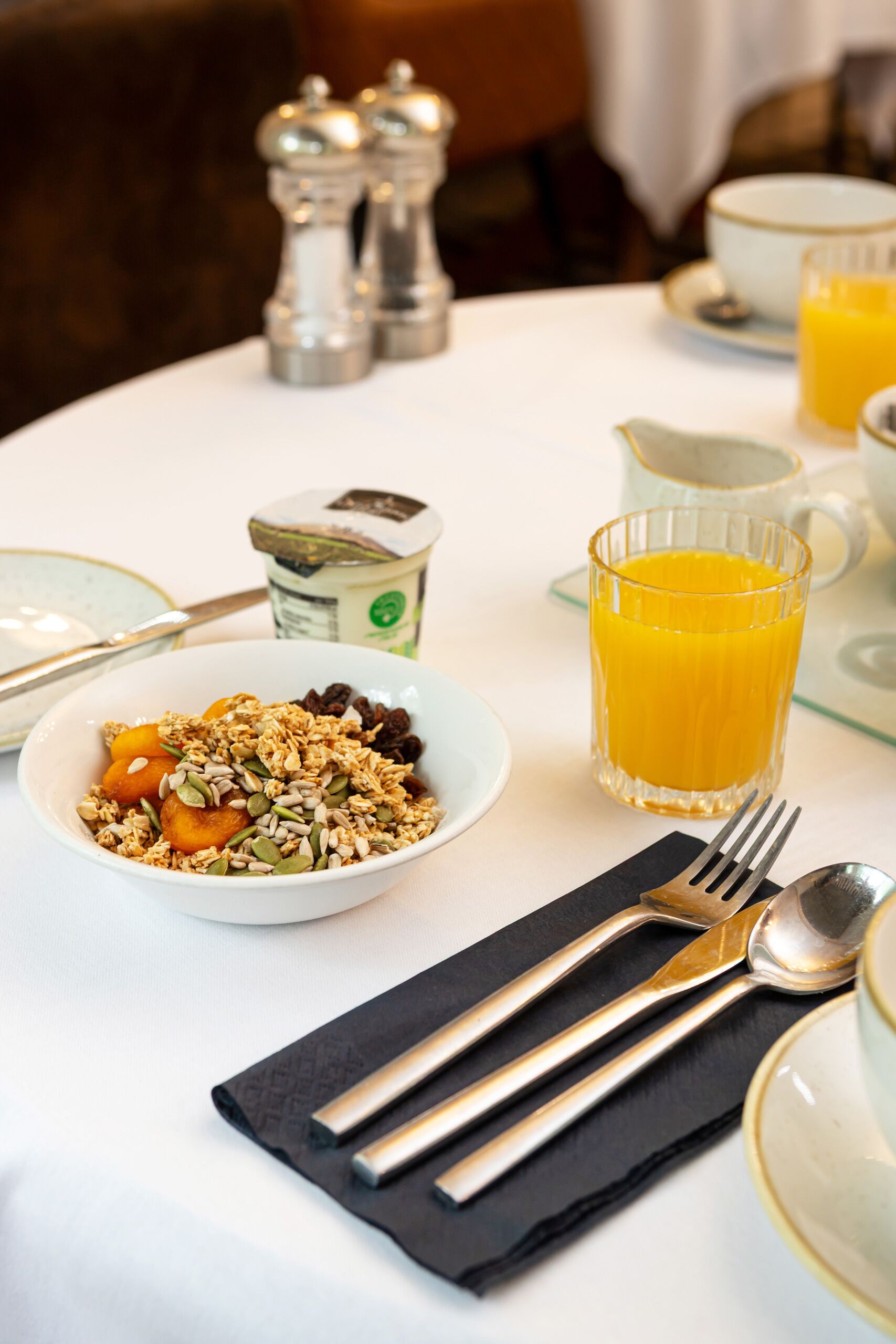 A breakfast setting with a bowl of cereal, a glass of orange juice, and a cup of coffee on a table.