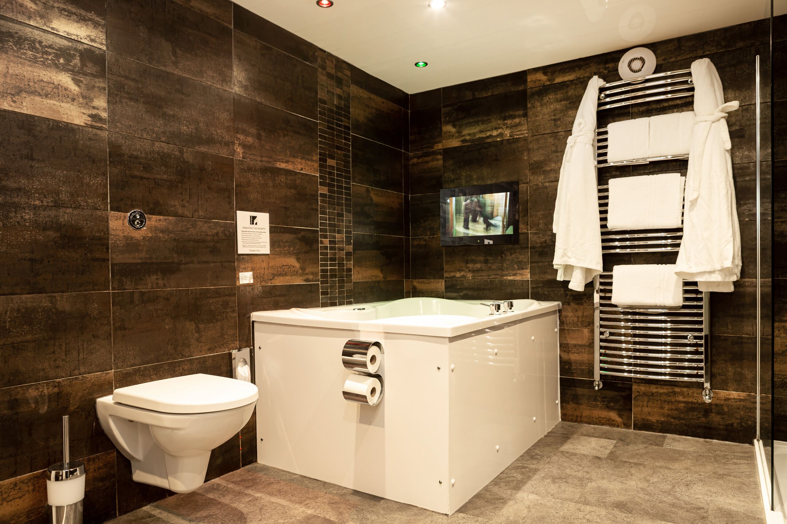 A modern bathroom with a bathtub, toilet, and towel rack.