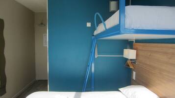 Ein Schlafzimmer mit Etagenbett, blauer Wand, Holz-Kopfteil und weißem Bett.