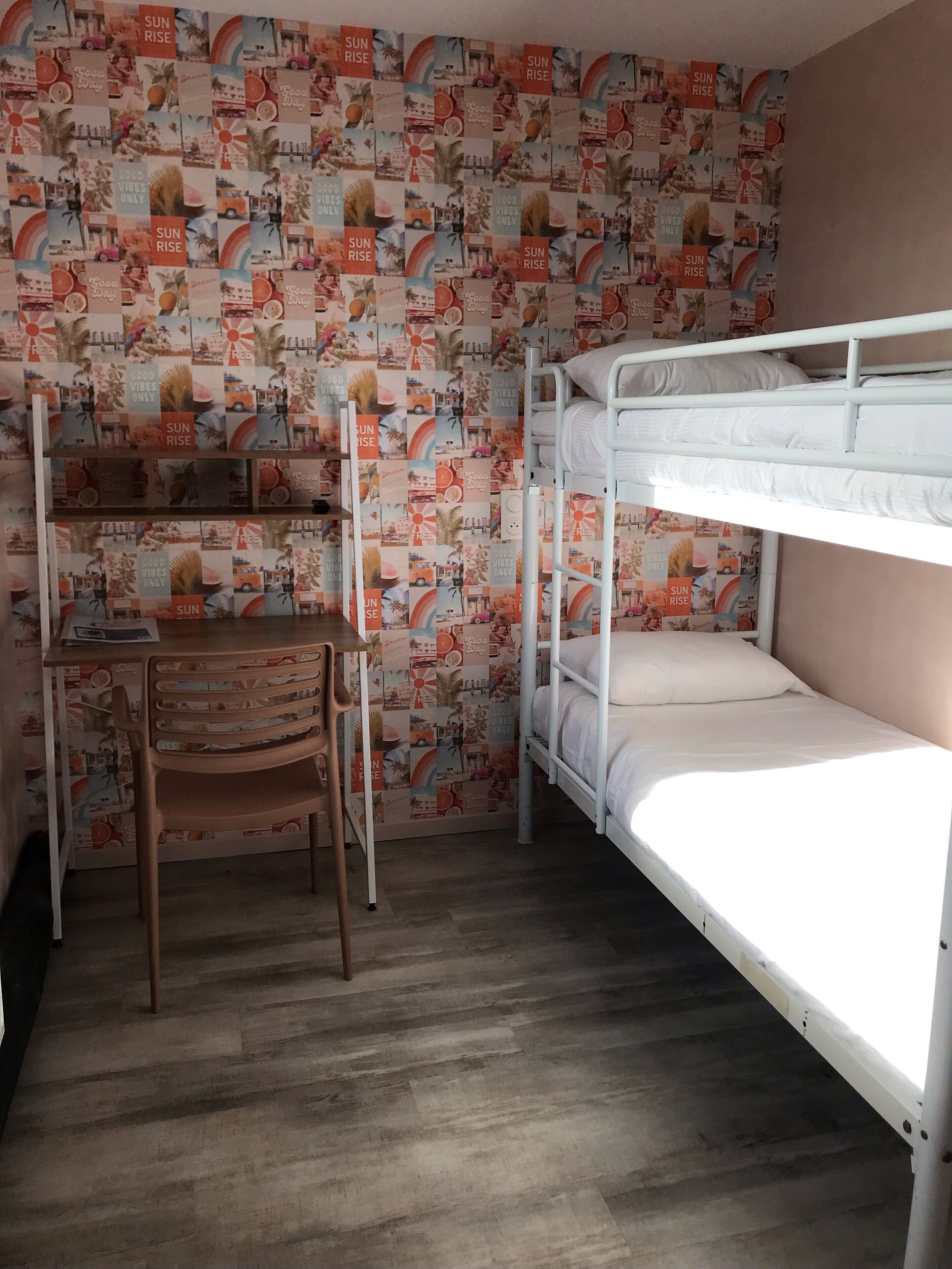 A room with bunk beds, a desk, and a chair.