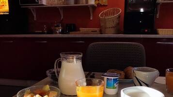 Una mesa de desayuno con cruasanes, fruta, jugo y café.