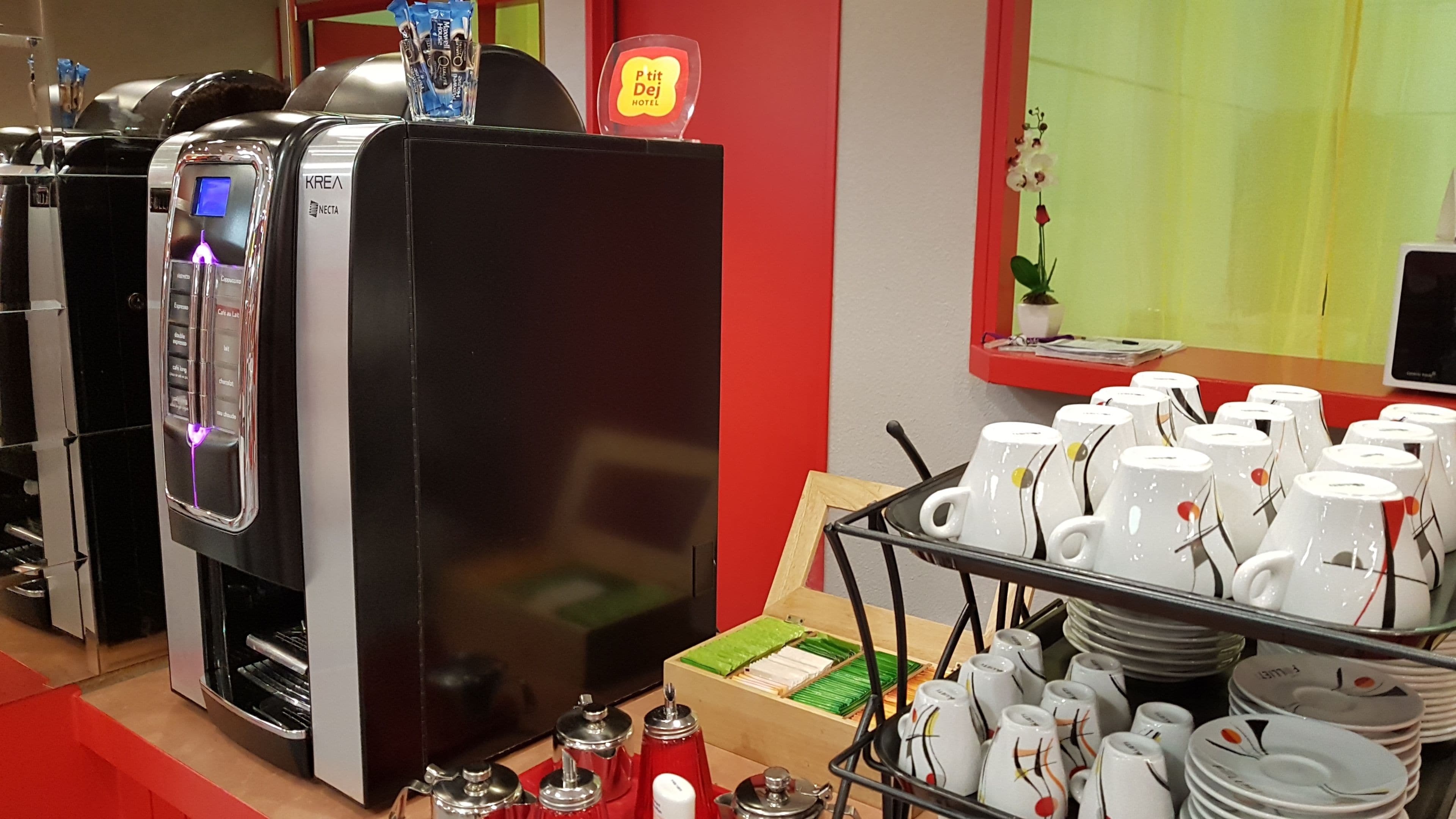 En kaffemaskin, en skylt för hotellet Prit Deij och en utställning med kaffekoppar och tallrikar.