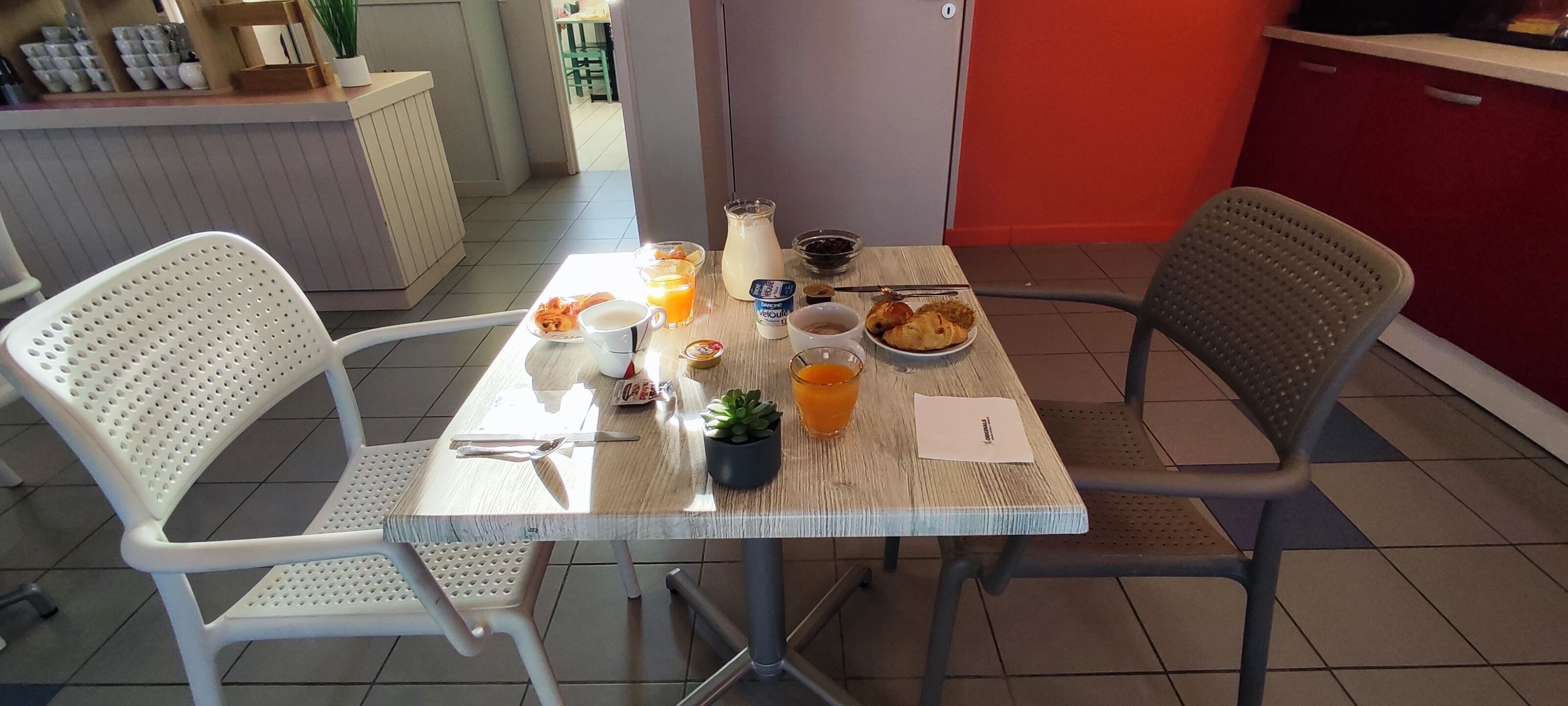 A breakfast table with a pitcher of orange juice, a bowl of fruit, a plate of croissants, and a cup of coffee.