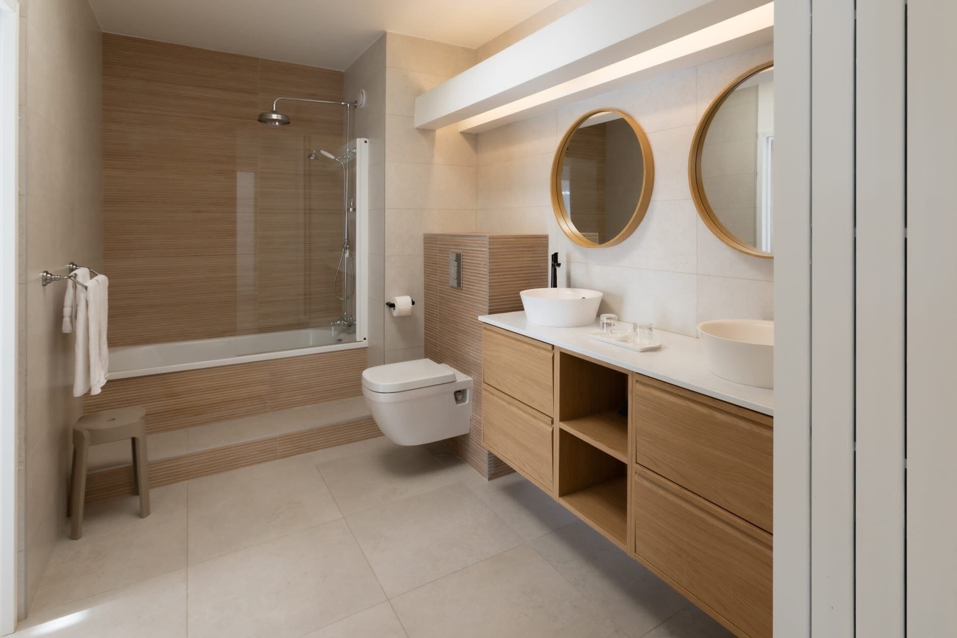 Un baño moderno con bañera, inodoro y tocador con dos espejos.