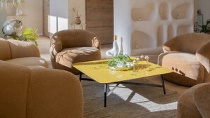 A modern living room with a yellow coffee table, comfortable seating, and a decorative wall. - Hotel Astoria (Saint-Etienne)