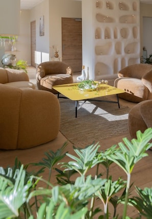 A modern living room with a yellow coffee table, comfortable seating, and a decorative wall. - Hotel Astoria (Saint-Etienne)