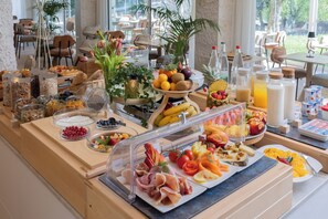 A buffet with various food items, including fruits, vegetables, and meats, arranged on a table. - Hotel Astoria (Saint-Etienne)