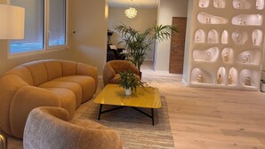 A modern living room with a sofa, armchair, and a yellow coffee table with a plant. - Hotel Astoria (Saint-Etienne)