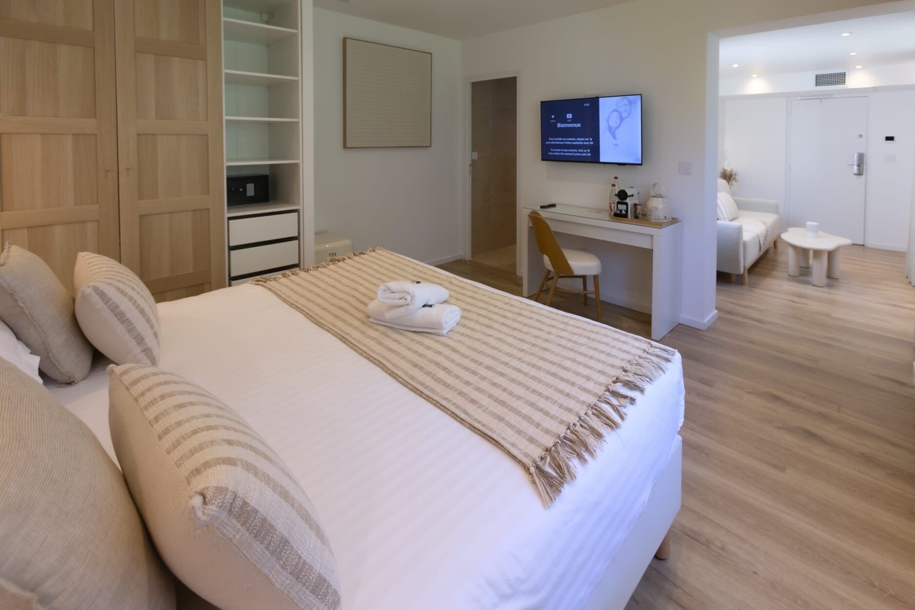 A hotel room with a bed, a desk, a chair, a television, and a wardrobe.