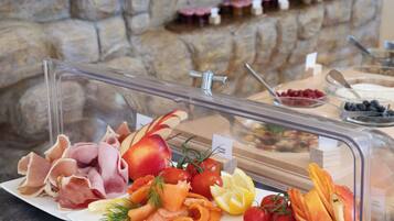 A buffet with various food items including meats, cheeses, and fruits.