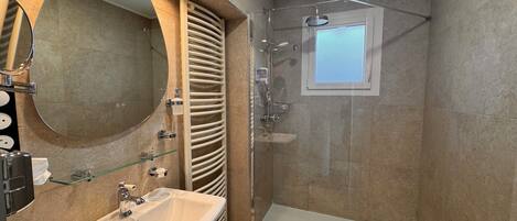 A modern bathroom with a glass-enclosed shower, a large mirror, and a white sink.