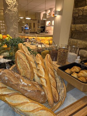 A bakery display with various types of bread, including baguettes and croissants, and a selection of fruits and vegetables.